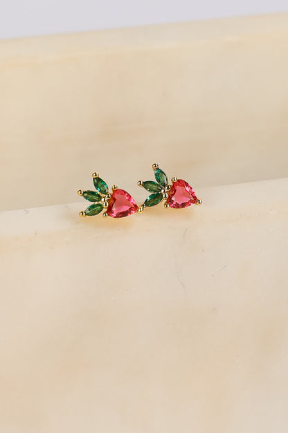 Pair of earrings with heart-shaped gemstones on a beige surface