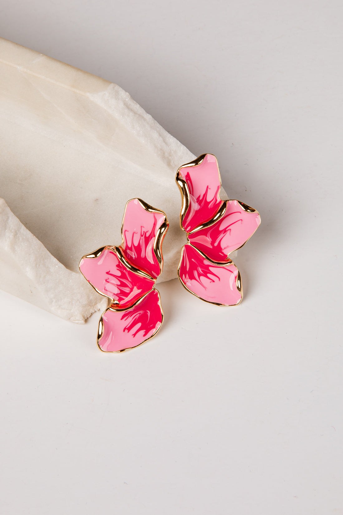 Pink butterfly-shaped earrings on a light background