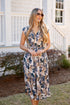 Woman wearing a floral dress standing outdoors near a house.
