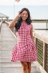 Woman wearing a red and white checkered dress on a wooden pier.