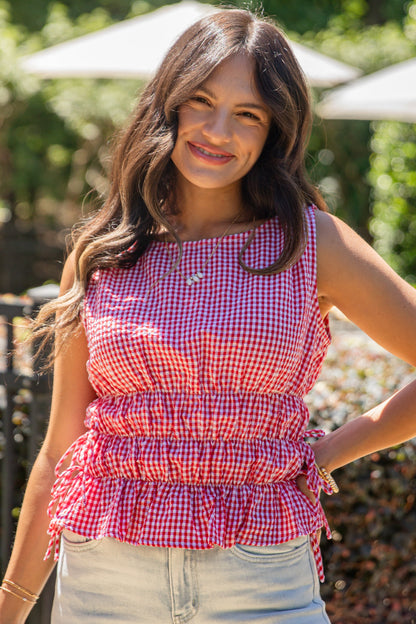 Woman wearing a red and white checkered top with a blurred outdoor background