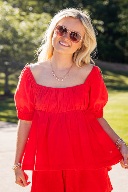 Woman wearing a red outfit with sunglasses outdoors