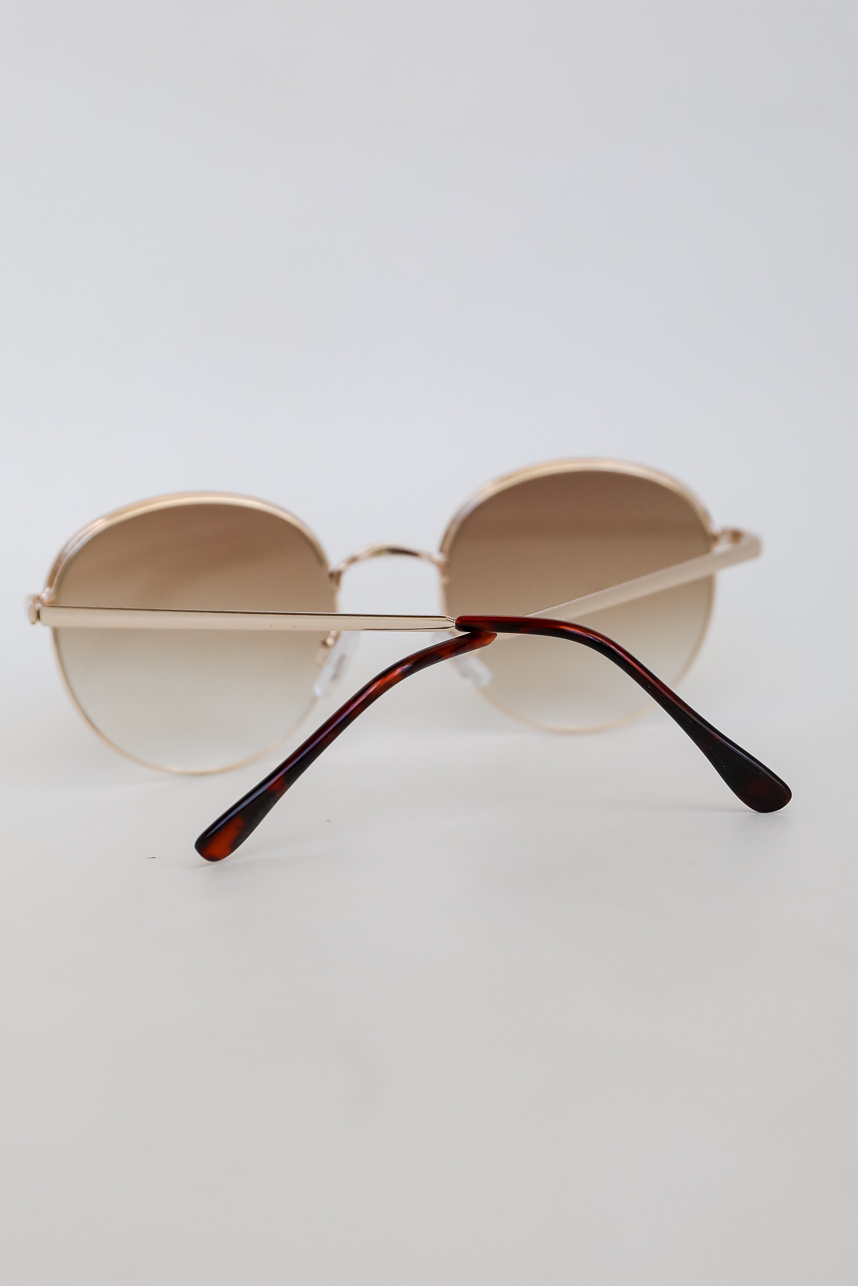 Sunglasses with gradient lenses and tortoiseshell arms on a light gray background