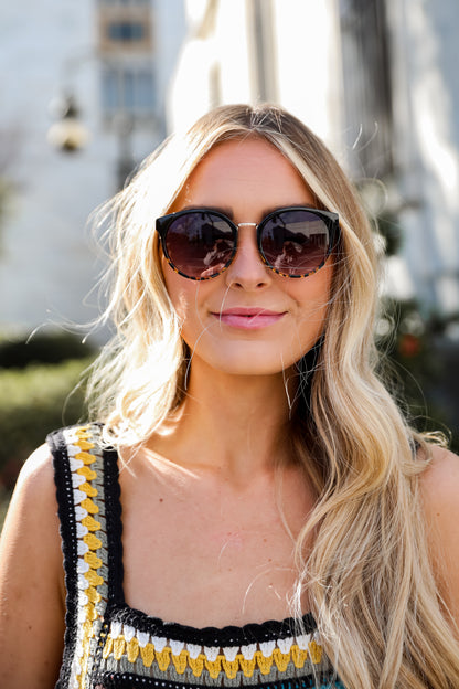 Sunglasses with dark lenses and tortoiseshell frame on a light gray background