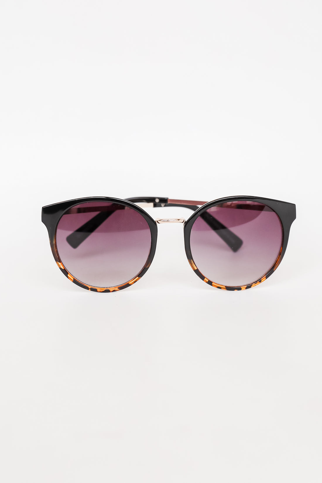 Sunglasses with tortoiseshell frame and gradient purple lenses on a white background