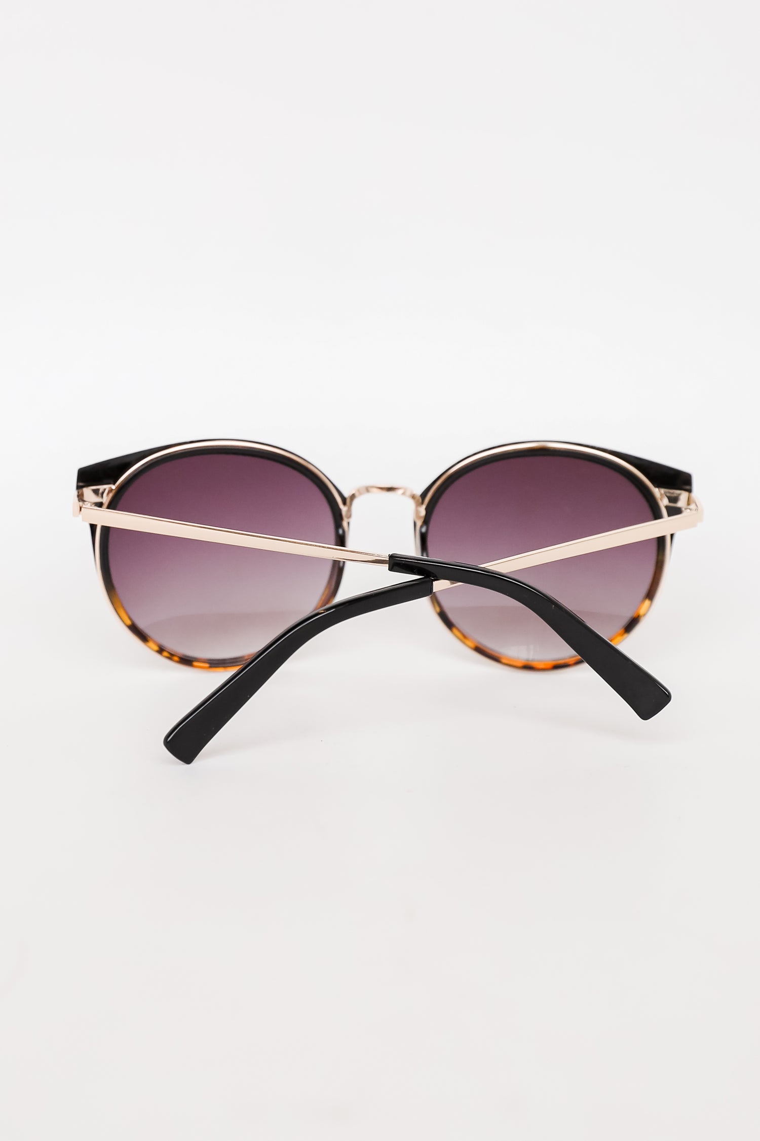 Sunglasses with gold frame and black arms on a white background