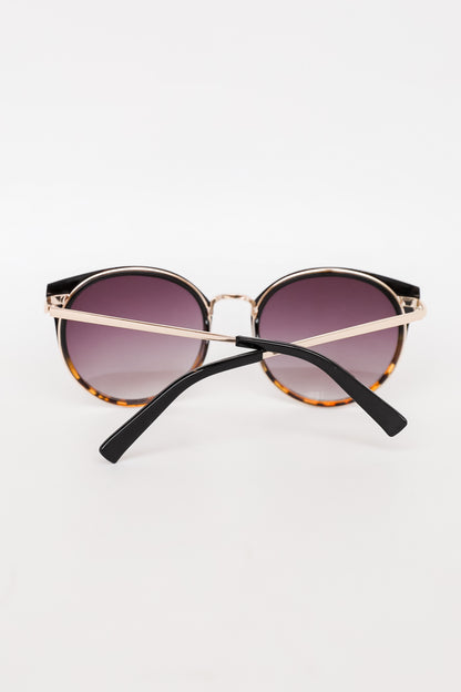 Sunglasses with gold frame and black arms on a white background