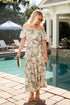 Woman in a leaf-patterned dress standing by a poolside.