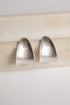 Pair of silver earrings on a light wooden stick against a white background