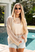Woman wearing a beige mesh top and sunglasses by a pool