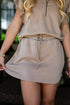 Person wearing a beige outfit with a drawstring skirt.