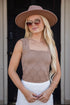 Woman wearing a brown top and white skirt standing outdoors with a blurred background