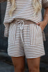 A close-up of a person wearing a matching brown and white striped lounge set, featuring a drawstring waist belt and shorts with a textured fabric.