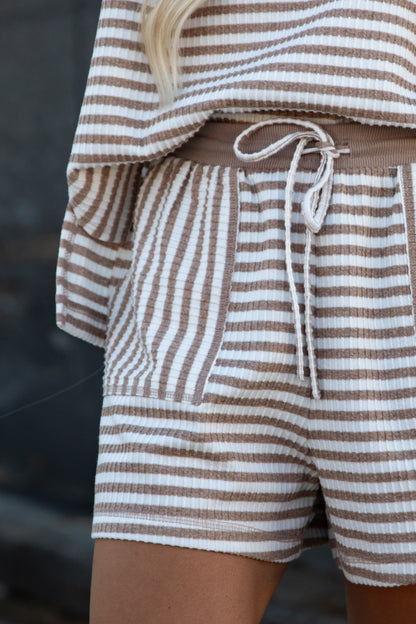 Close-up of a person wearing brown and white striped waffle-knit shorts with a matching drawstring waist and a matching striped top.