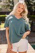 Woman in a teal shirt and white shorts standing by a pool