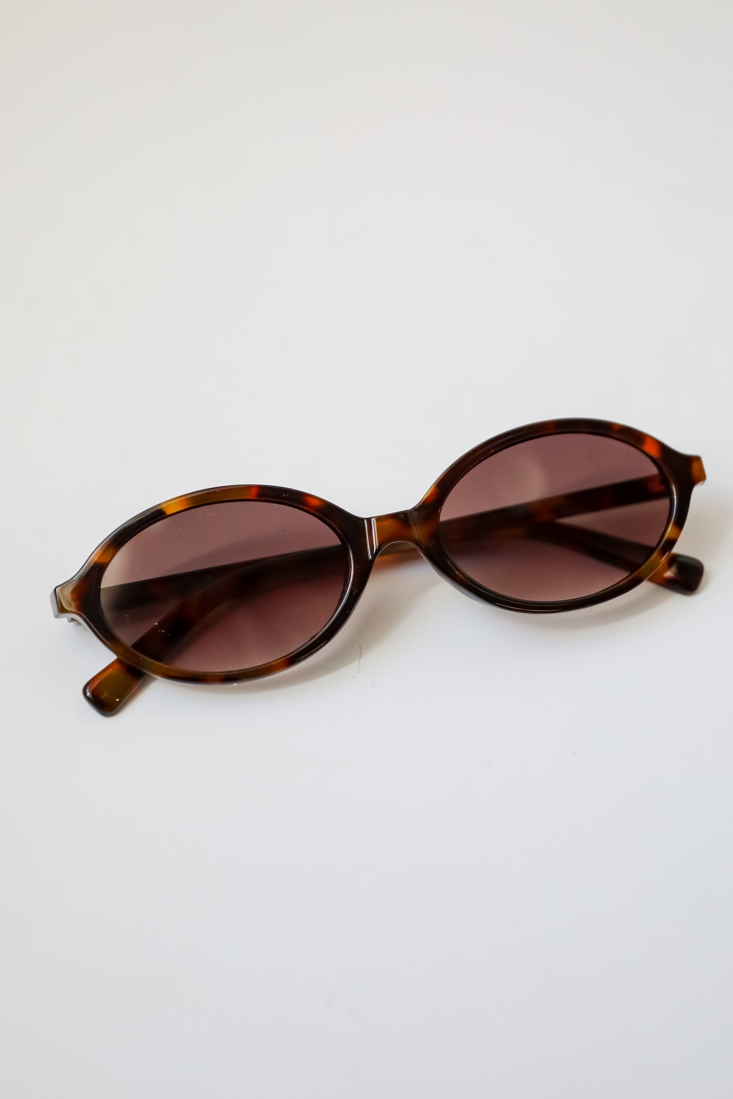 Sunglasses with tortoiseshell frame and brown lenses on a white background