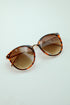 Sunglasses with tortoiseshell frame and gradient lenses on a light blue background