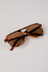 Sunglasses with tortoiseshell frame and brown lenses on a light gray background