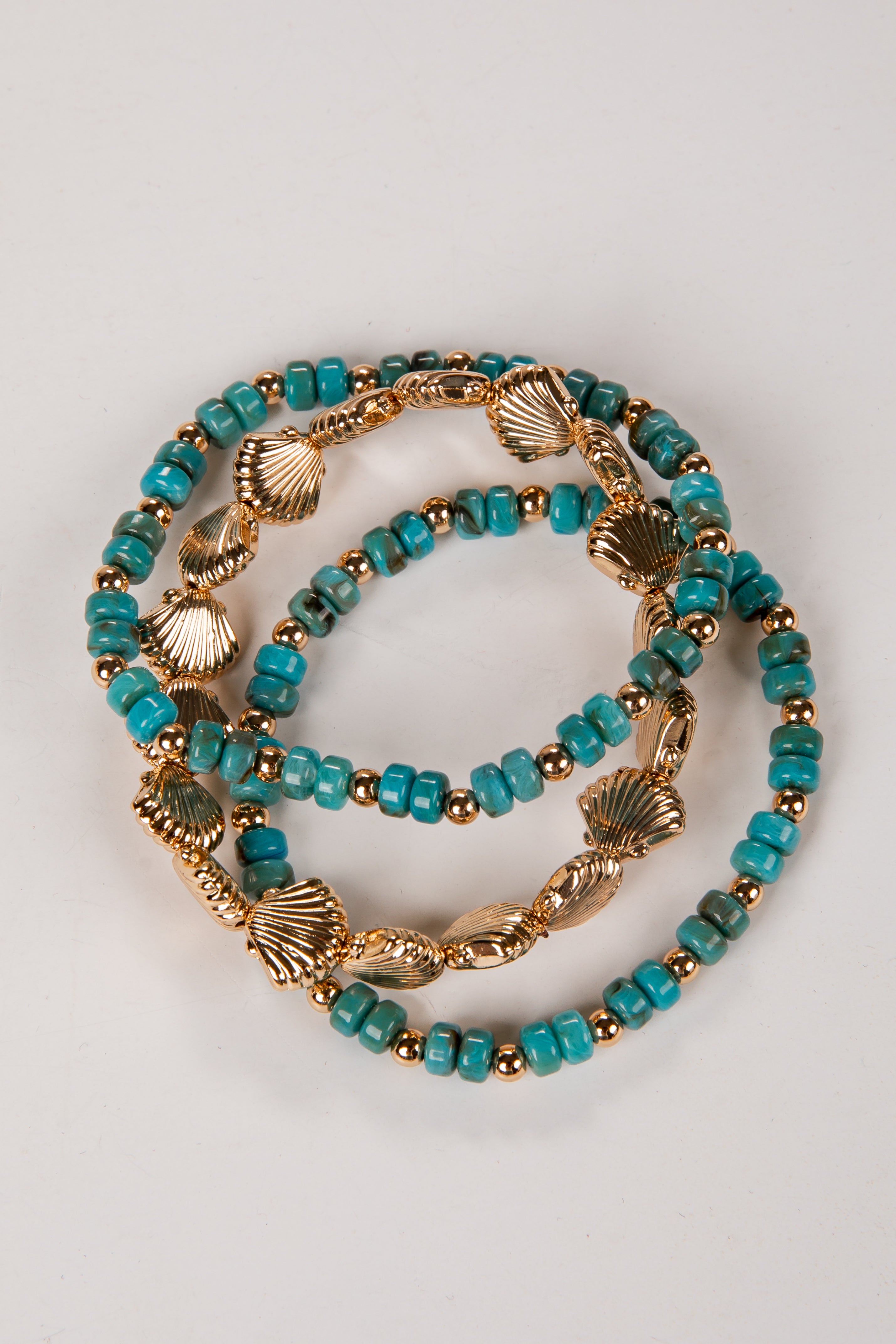 Two turquoise beaded bracelets with gold accents on a light gray background