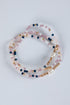 Set of beaded bracelets with pink, blue, and gold beads on a light gray background