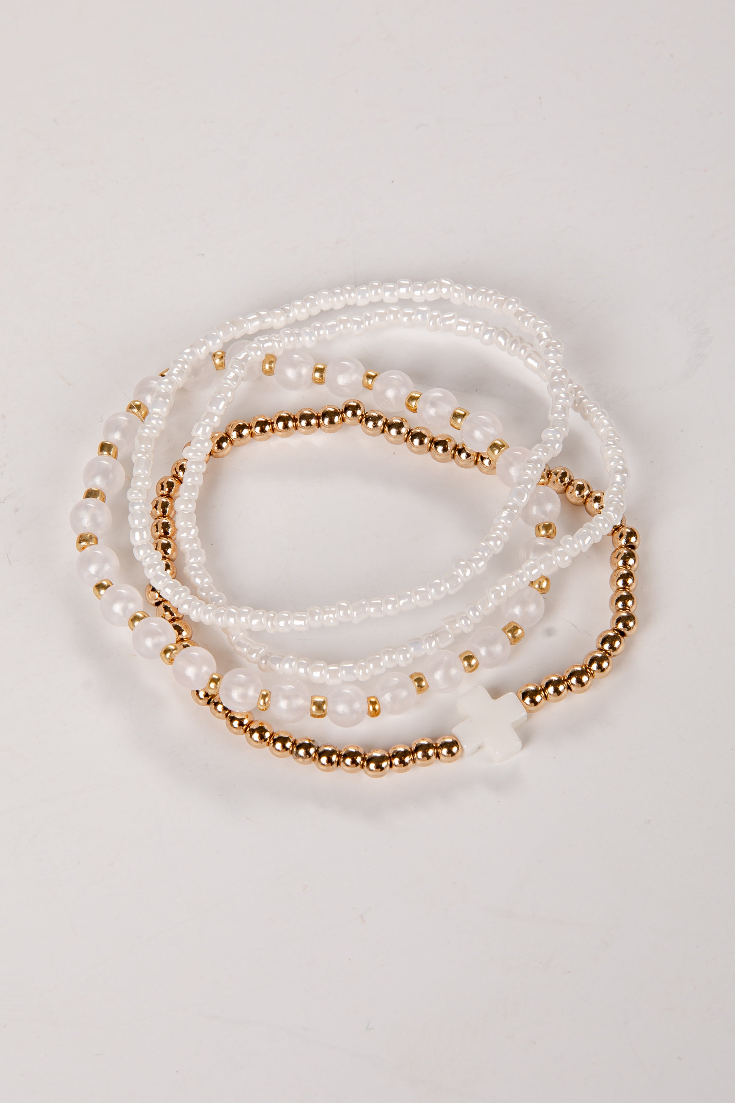 Set of pearl and gold beaded bracelets on a light background