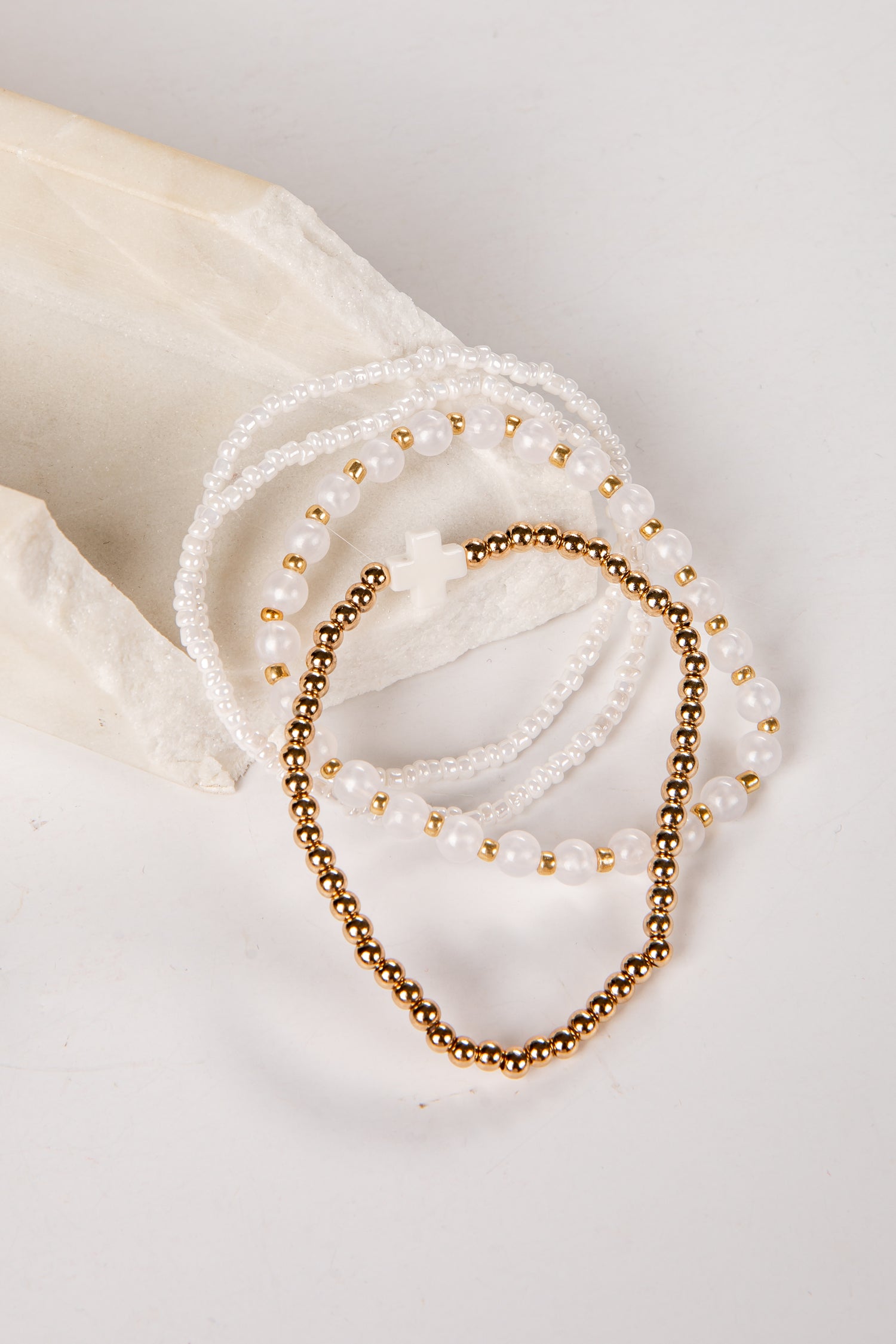 Two pearl and gold beaded bracelets on a white surface