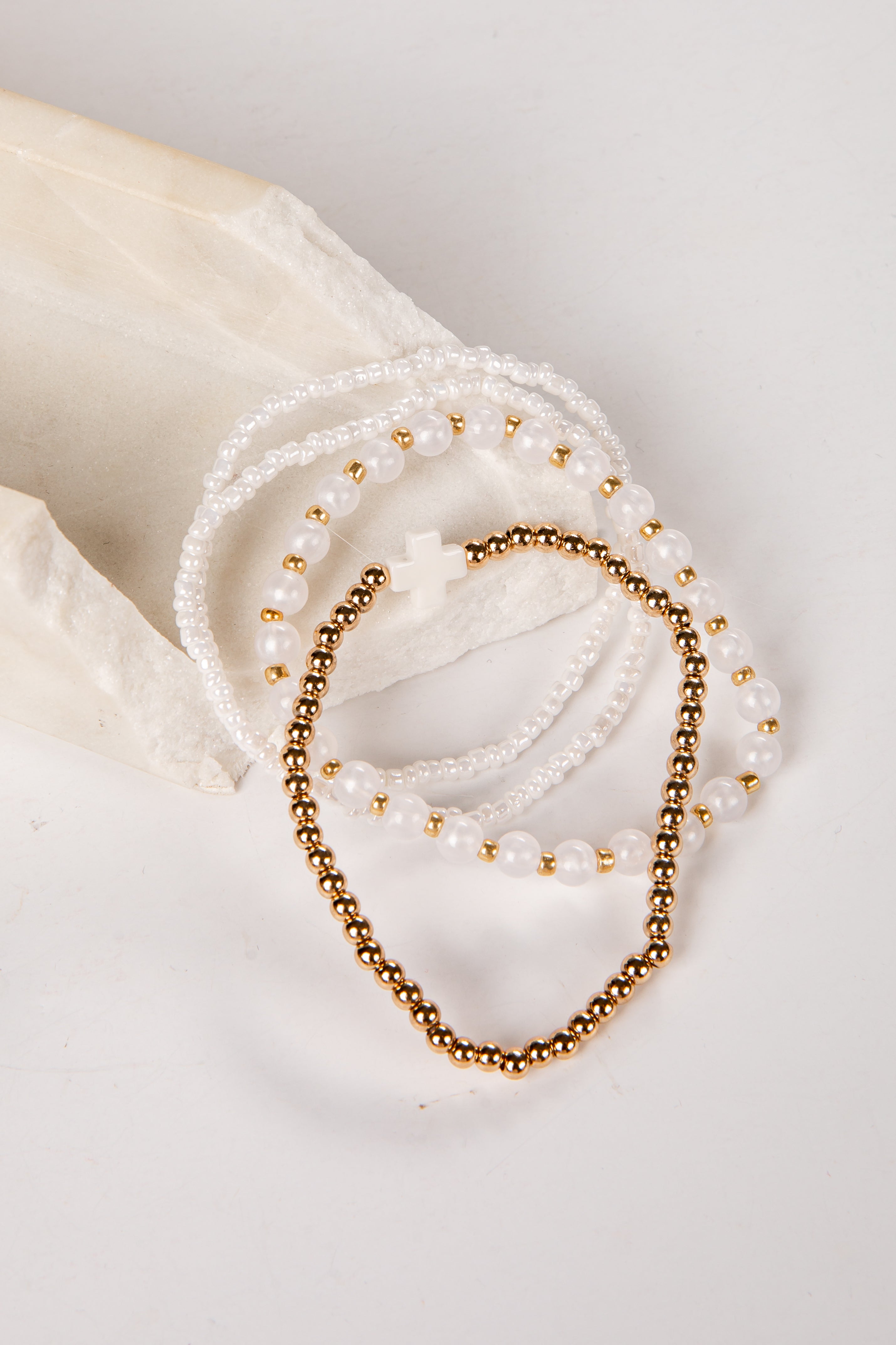 Two pearl and gold beaded bracelets on a white surface