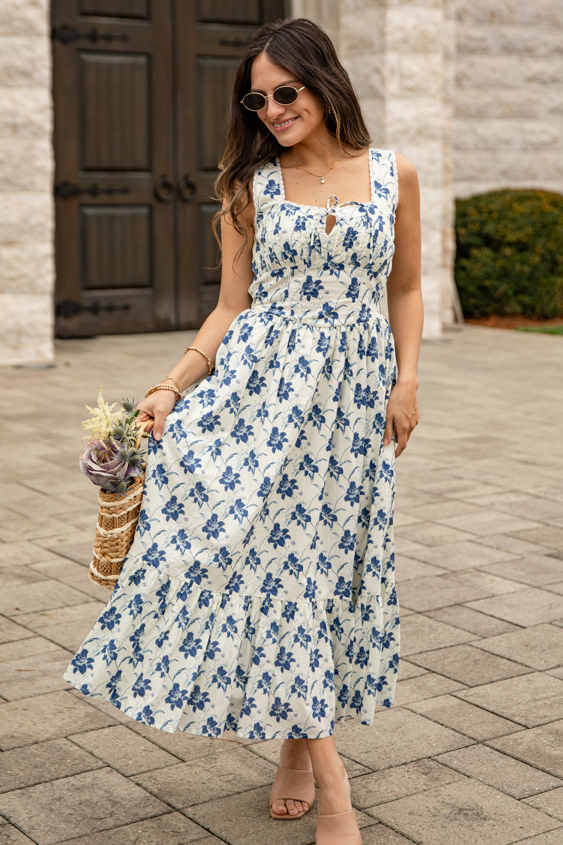 Woman in a floral dress standing in front of a stone building.