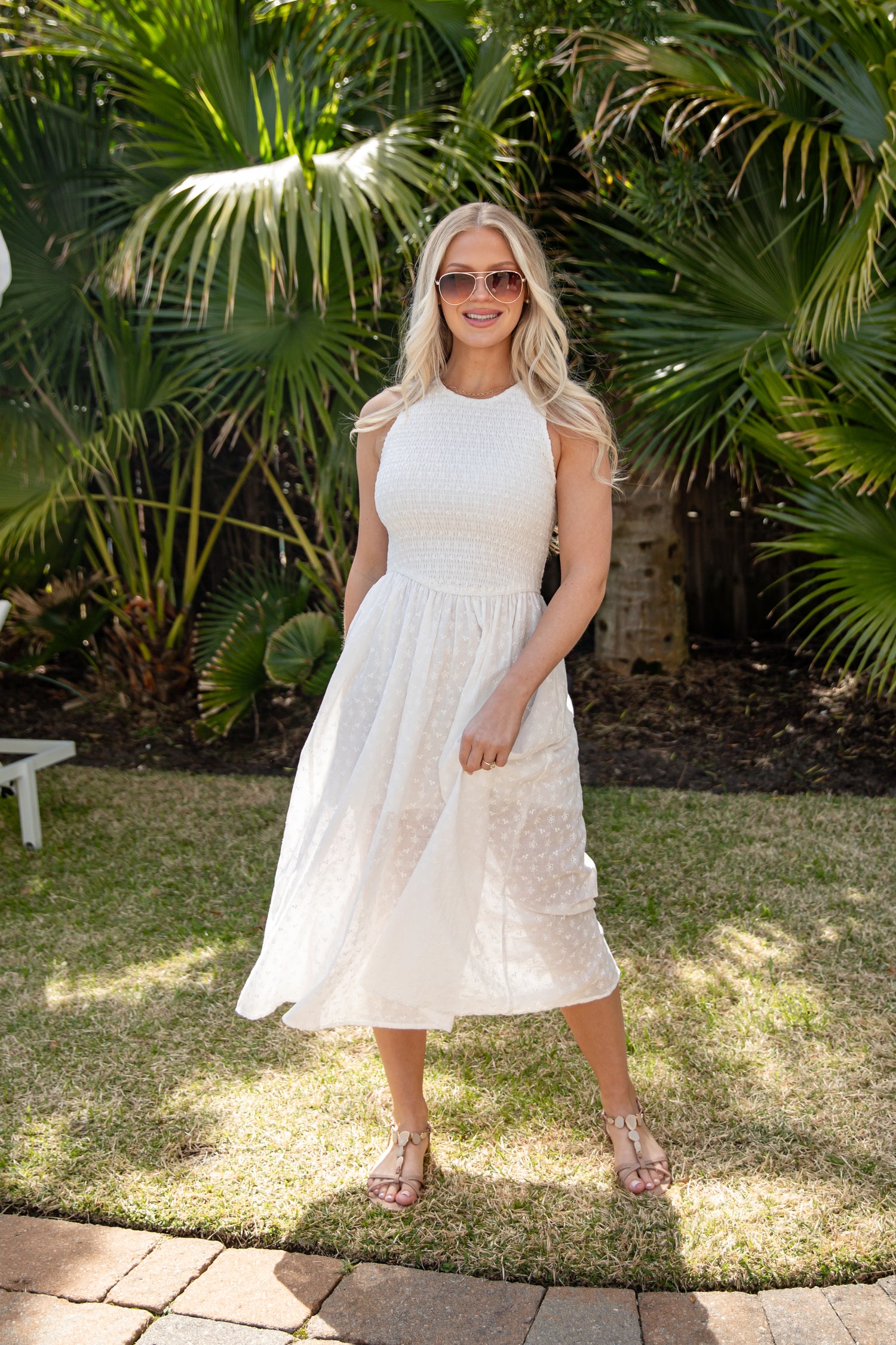Woman in a white dress standing outdoors with palm trees in the background