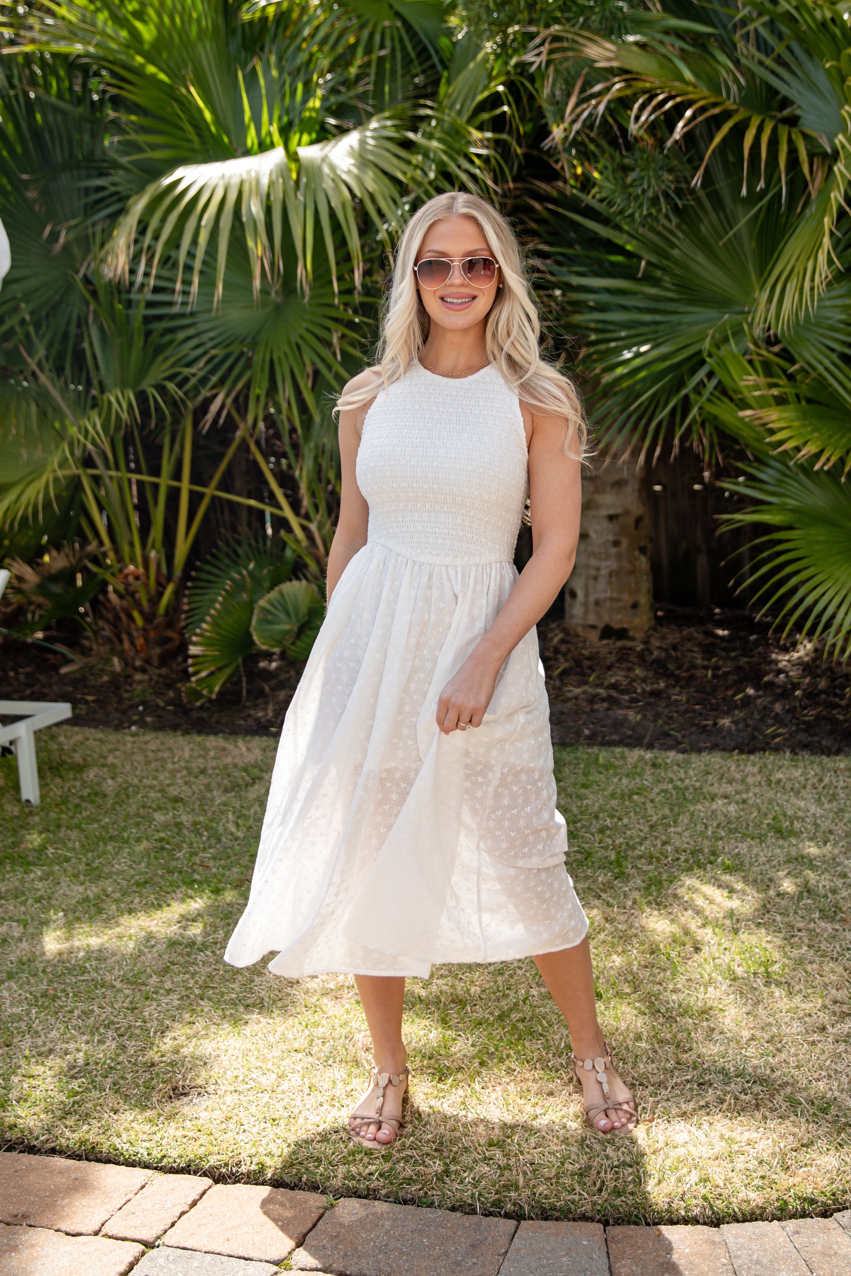 Woman in a white dress standing outdoors with palm trees in the background