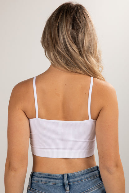 Person wearing a white crop top and blue jeans against a plain background