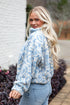 Woman wearing a blue floral jacket and jeans standing outdoors.