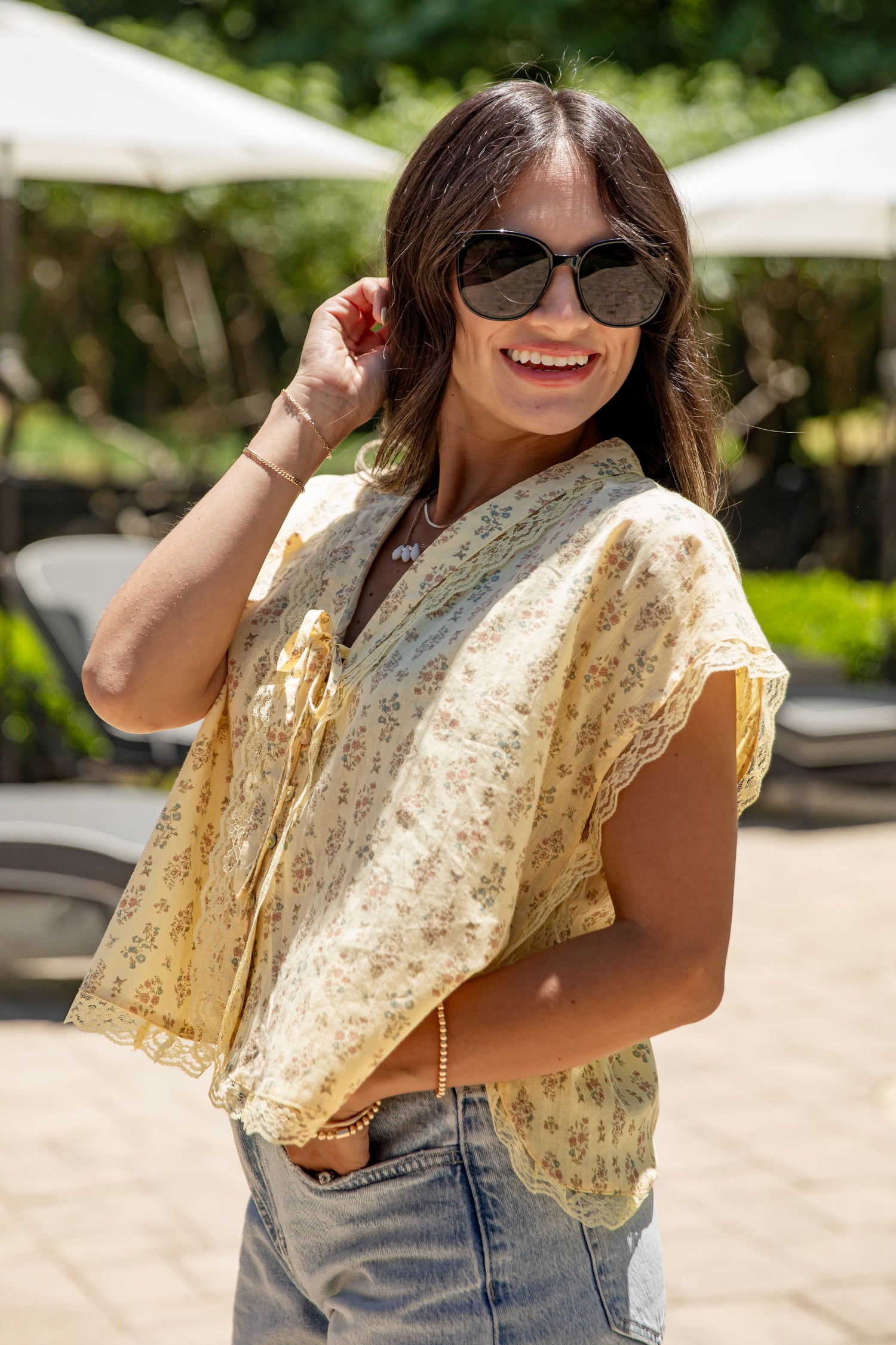 Woman wearing sunglasses and a floral blouse in an outdoor setting