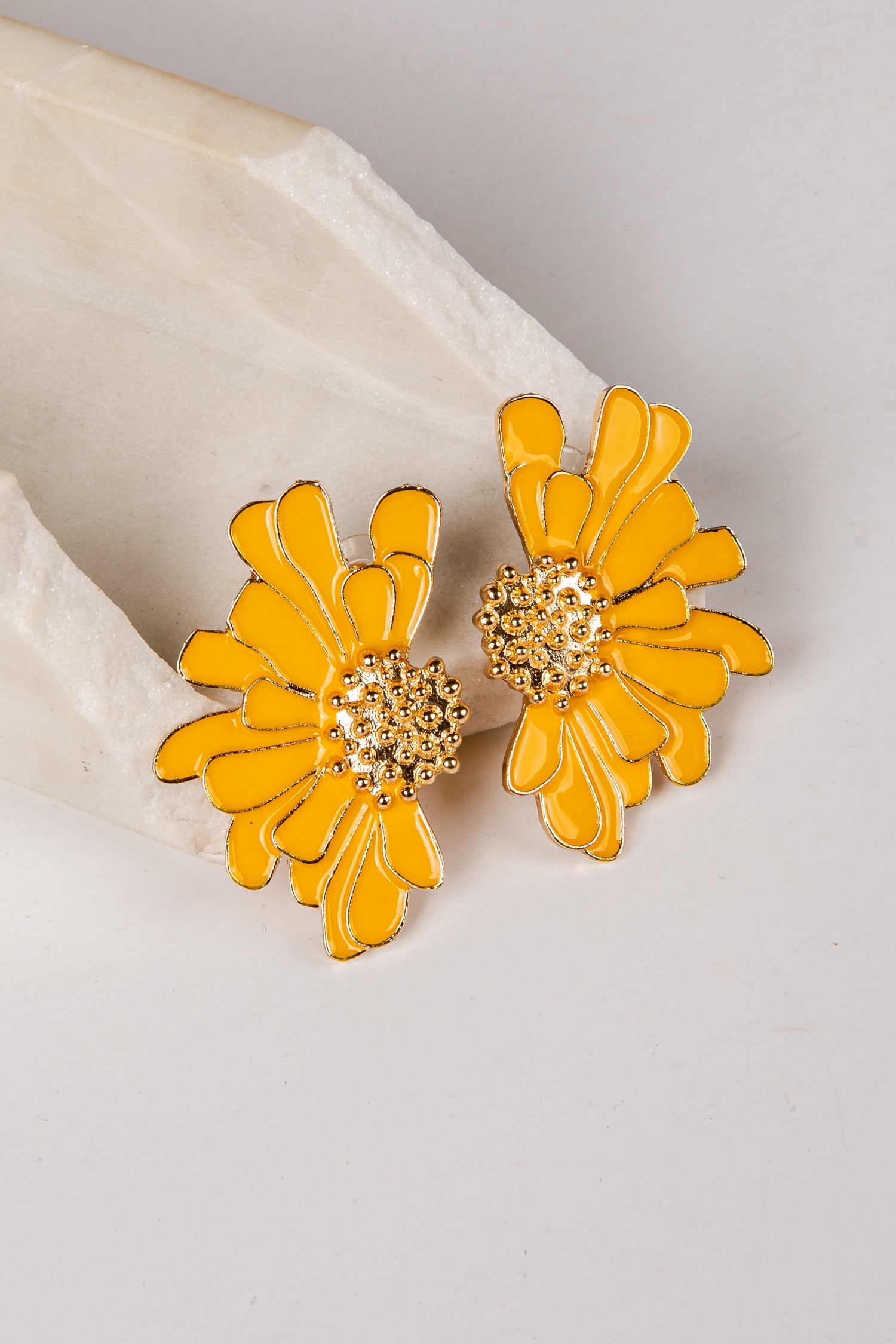 Yellow flower-shaped earrings on a light gray background