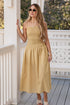 Woman in a yellow dress standing on a porch