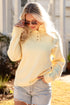 Woman wearing a yellow sweater and denim shorts outdoors.