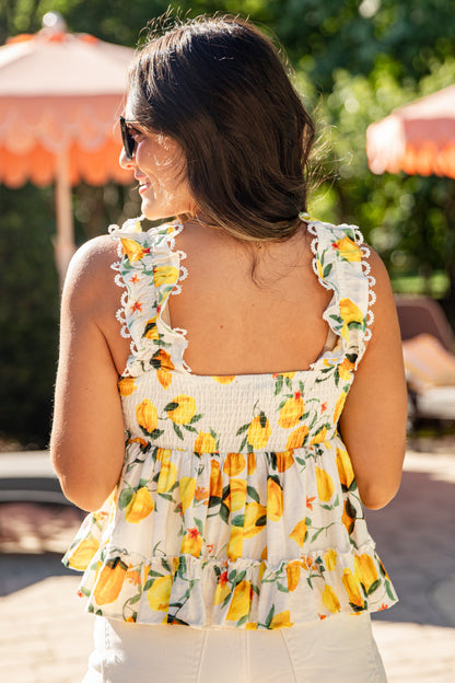 Woman wearing a lemon print top with a blurred outdoor background