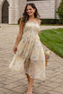 Woman in a floral dress standing on a paved walkway with a building in the background